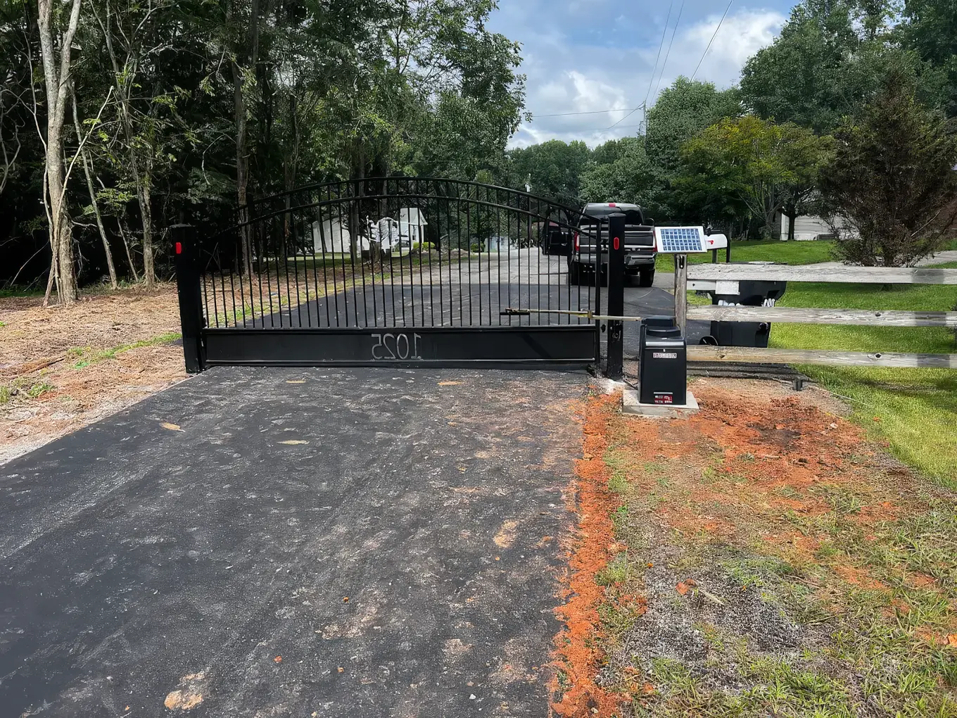 Arched slide gate with solar-powered opener on a rural Tennessee driveway
